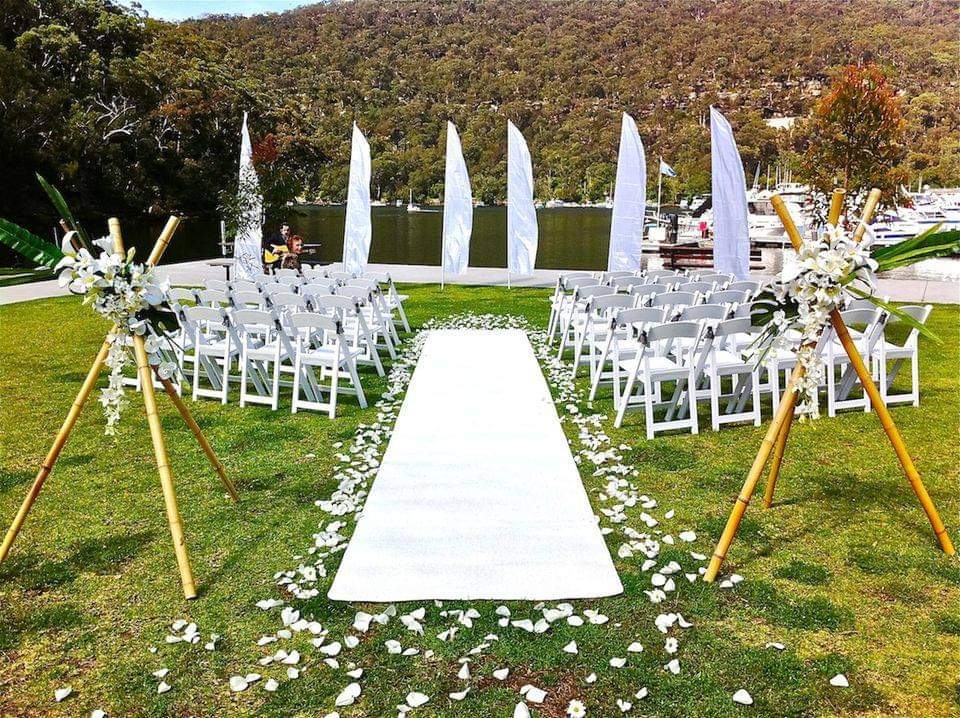 White wedding aisle carpet between rows of white chairs outdoors