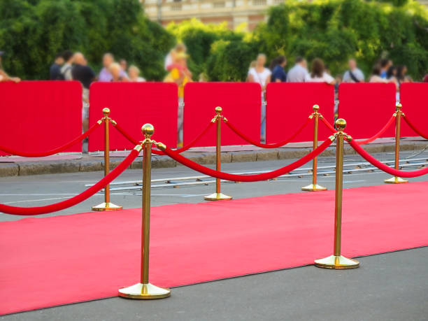 Red event carpet with gold bollards and red ropes